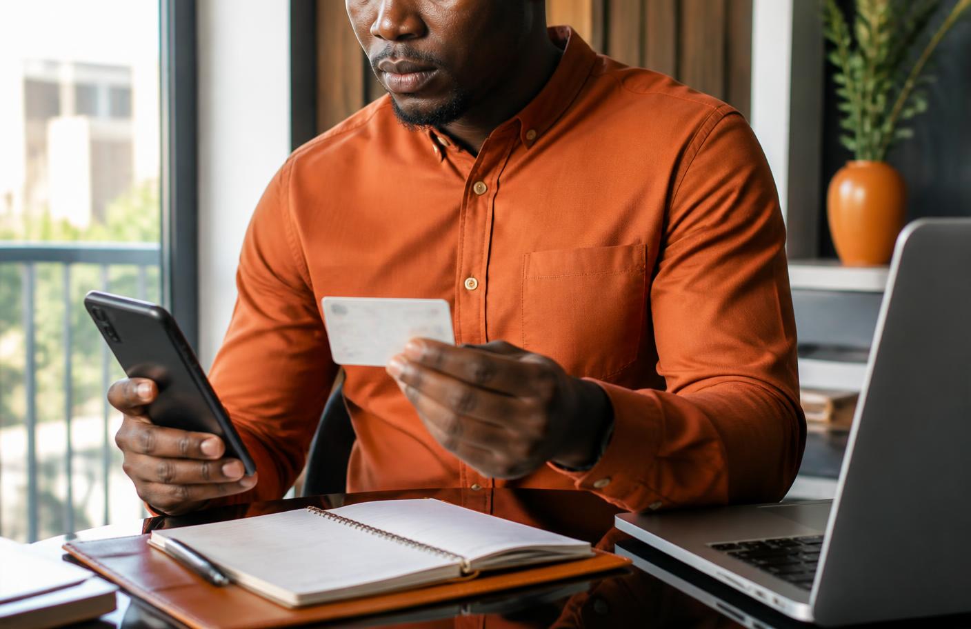 Nigerian professional securely checking an identity card and smartphone during digital verification